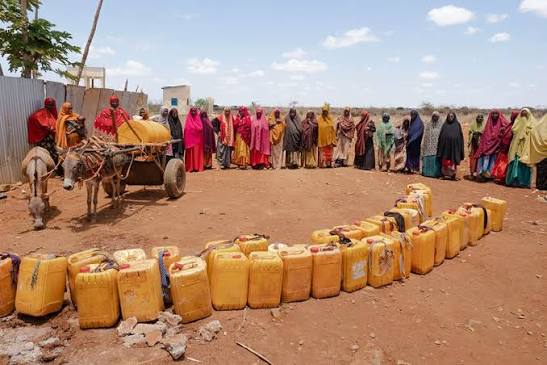 Community members standing beside water containers.